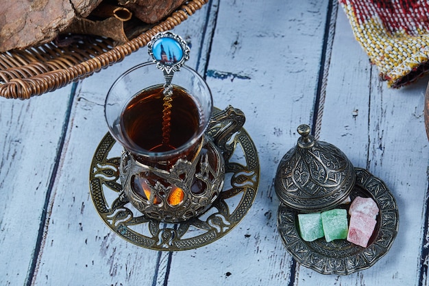 Photo gratuite thé noir dans une tasse en verre traditionnelle avec des bonbons sur une table en bois bleue