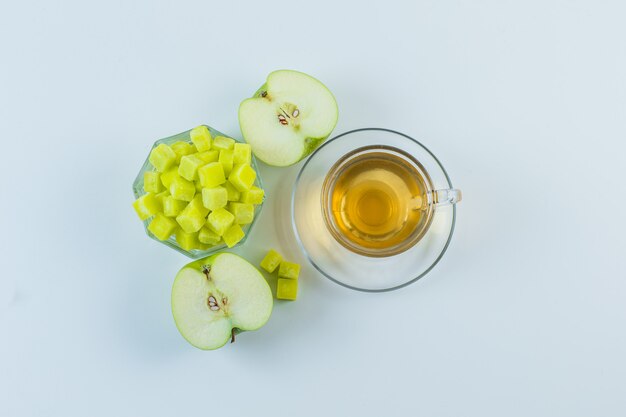 Thé à la pomme, cubes de sucre dans une tasse sur fond blanc, pose à plat.