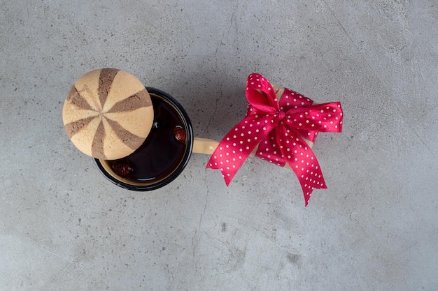 Thé à la rose de chien, un cookie et un paquet cadeau sur une table en marbre.