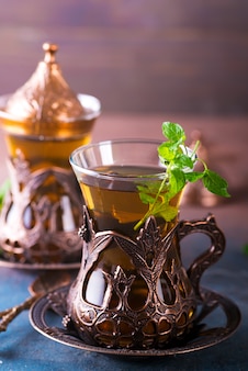 Thé turc traditionnel avec des feuilles de menthe dans un verre traditionnel sur du béton