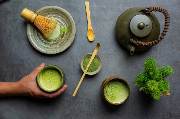 Thé vert chaud dans un verre à la crème garni de thé vert, décoré de poudre de thé vert.