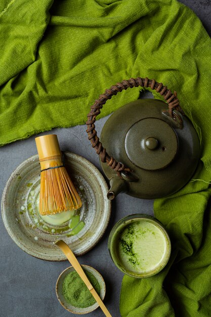 Thé vert chaud dans un verre à la crème garni de thé vert, décoré de poudre de thé vert.