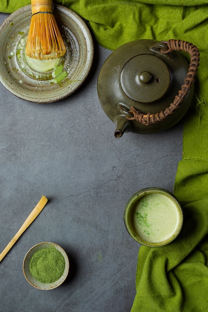 Thé vert chaud dans un verre à la crème garni de thé vert, décoré de poudre de thé vert.