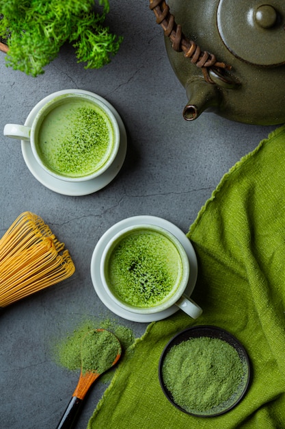 Thé vert chaud dans un verre à la crème garni de thé vert, décoré de poudre de thé vert.