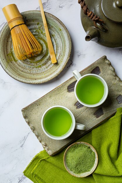 Thé vert chaud dans un verre à la crème garni de thé vert, décoré de poudre de thé vert.