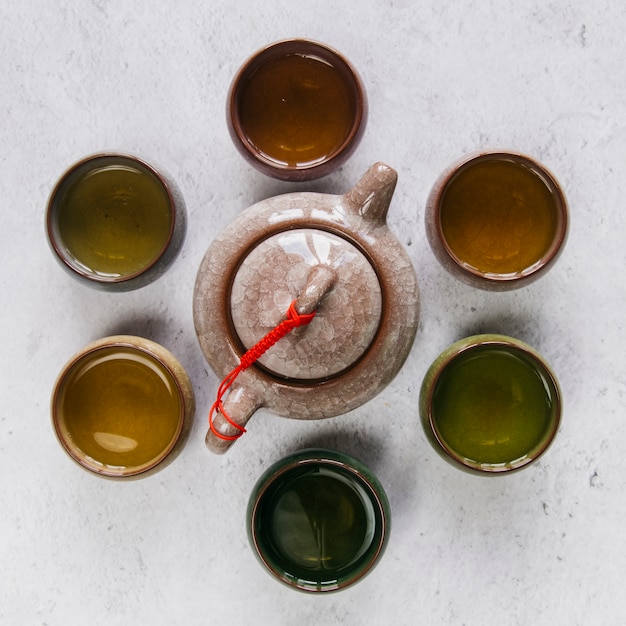 Théière en céramique d'argile chinoise entourée d'une tasse de thé à base de plantes sur fond