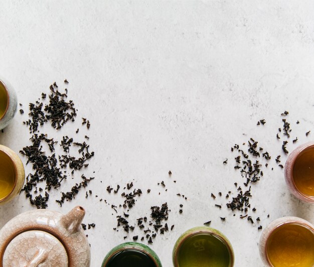 Théière en céramique avec une tasse de thé à base de plantes sur fond de béton