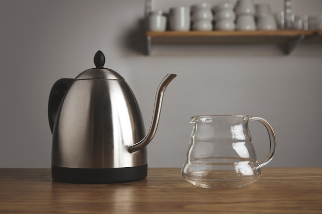 Théière métallique moderne avec pot transparent pour café filtré dans une table en bois épaisse dans un café