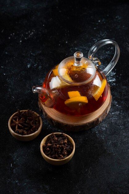 Une théière en verre avec du thé chaud et des clous de girofle séchés.