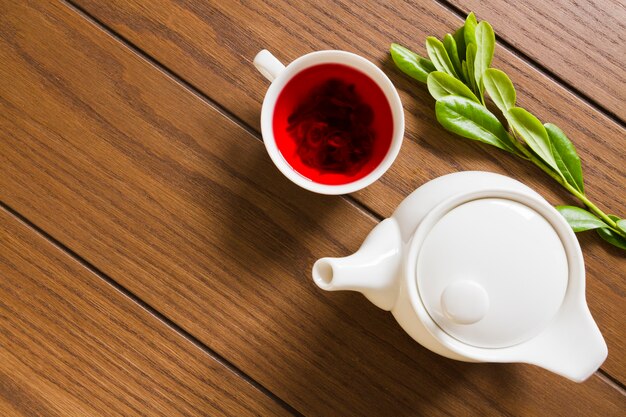 Théière vue du dessus avec tasse de thé et feuilles