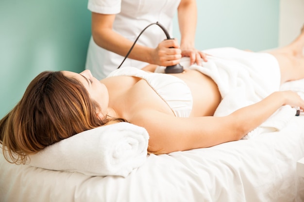 Thérapeute féminine donnant un traitement réducteur et réaffirmant à une cliente et se concentrant sur son ventre