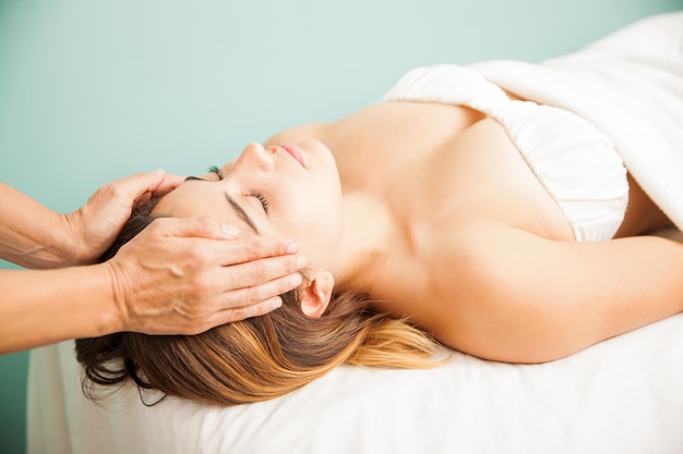 Thérapeute féminine équilibrant l'énergie d'un client lors d'une séance de reiki dans un spa de santé. Les deux mains sur la tempe