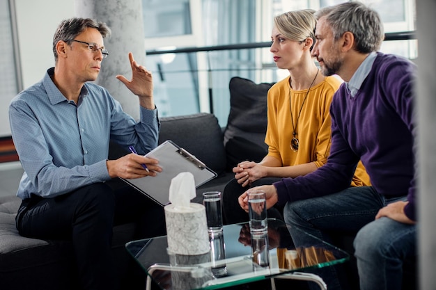 Thérapeute masculin parlant à un couple pendant le conseil matrimonial au bureau