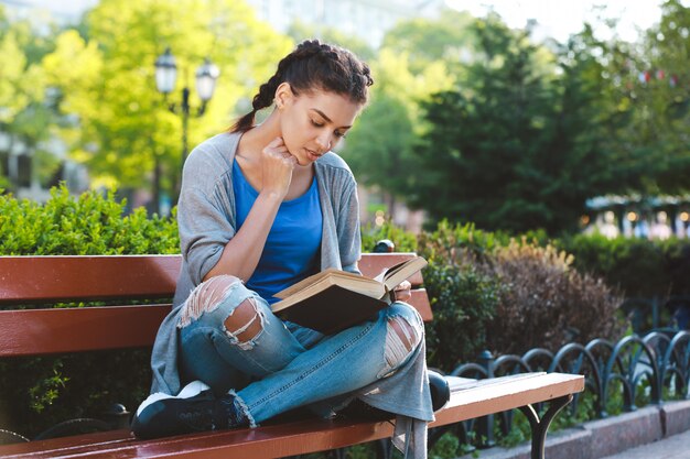 Thouhtful belle fille africaine lisant le livre