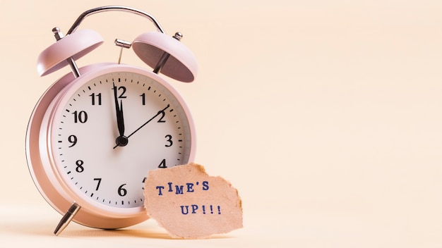 Times up text sur du papier déchiré près du réveil sur fond beige