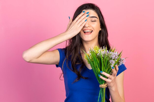 Timide belle fille tenant un bouquet de fleurs et tenant sa main sur son visage