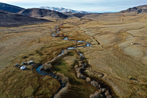 Tir aérien d'une rivière dans une grande prairie sèche