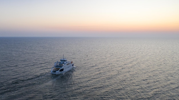 Tir Aérien D'un Yacht Naviguant Dans Une Mer Bleue Pendant Le Coucher Du Soleil