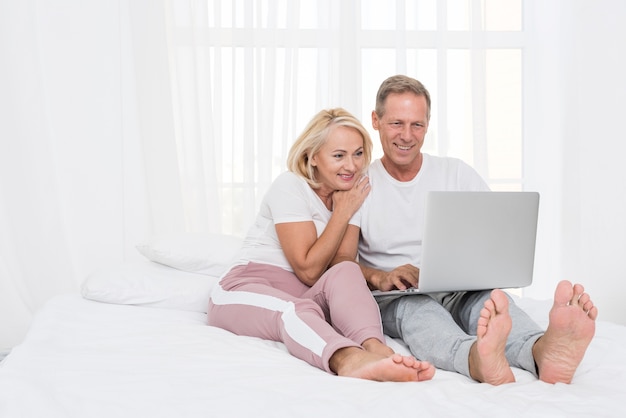 Tir complet couple heureux avec un ordinateur portable dans la chambre
