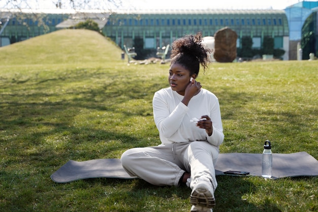 Photo gratuite tir complet femme assise sur un tapis de yoga