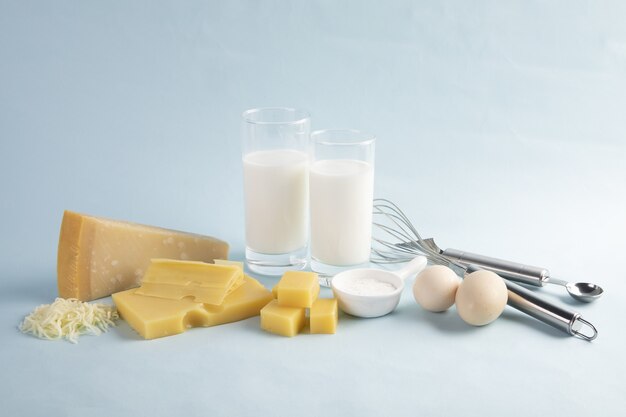 Tir d'un délicieux plateau de fromages avec du lait et des œufs isolés sur un fond bleu clair