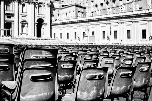 Tir à l'échelle de gris de chaises en plastique noir sur une place à Rome