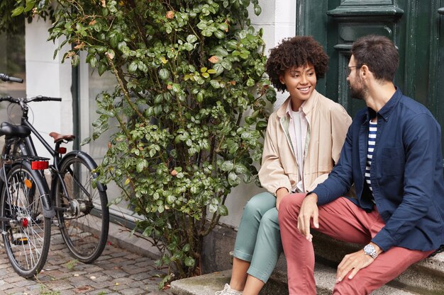 Tir extérieur de couple assis sur les escaliers du café