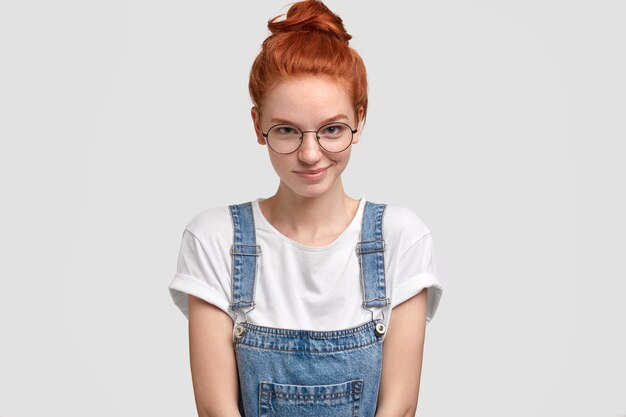 Tir horizontal de la jeune femme européenne au gingembre agréable à lunettes rondes transparentes