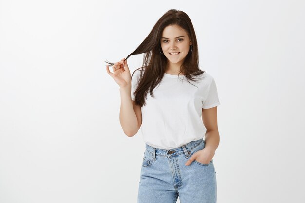 Tir horizontal de la jeune femme posant contre le mur blanc