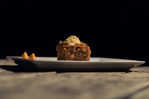 Photo gratuite tir horizontal d'un morceau de gâteau sur une plaque blanche sur une surface en bois