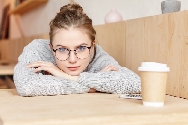 Tir à l'intérieur d'une femme adorable rêveuse portant des lunettes rondes