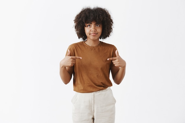 Photo gratuite tir à l'intérieur d'une femme afro-américaine intense d'être malheureux et mécontent d'être choisi par quelqu'un se pinçant les lèvres et tirant un sourire déçu regardant gauche pointant sur elle-même