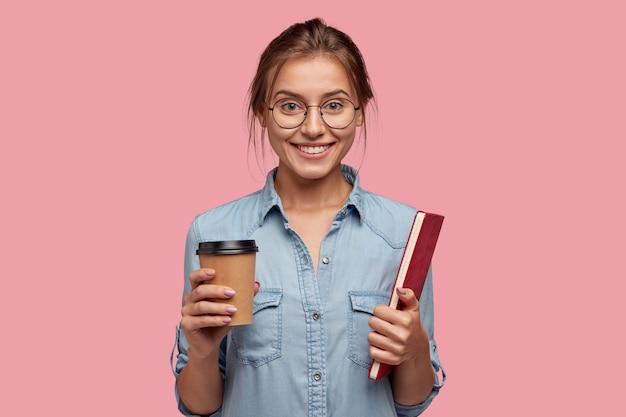 Tir intérieur d'une femme caucasienne heureuse tient une tasse de café jetable