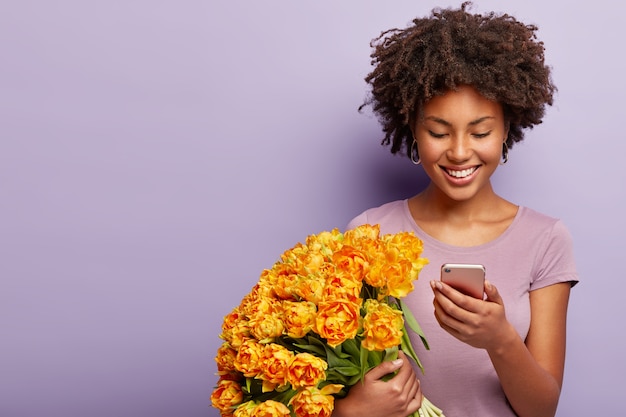 Tir à l'intérieur d'une femme joyeux anniversaire célèbre une occasion spéciale, tient le bouquet orange