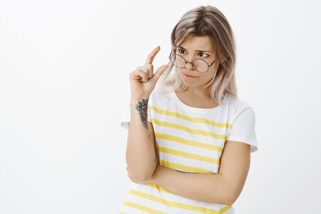 Tir intérieur de jolie jeune fille blonde avec des lunettes posant dans le studio