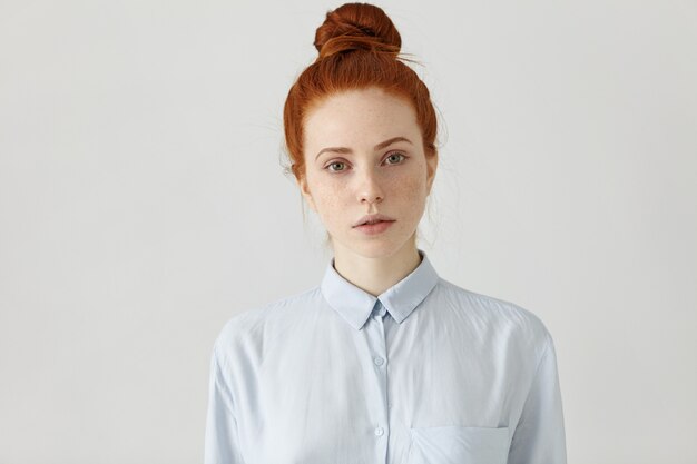 Tir intérieur de la jolie jeune rousse aux taches de rousseur caucasien employé de bureau avec chignon