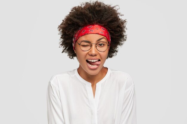 Tir isolé du contenu belle fille clignote avec les yeux, colle la langue, porte un bandeau rouge