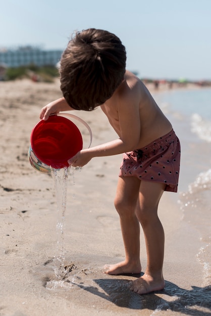 Photo gratuite tir latéral d'un enfant jouant avec un seau de sable
