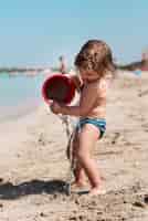 Photo gratuite tir latéral d'un enfant qui joue avec un seau de sable