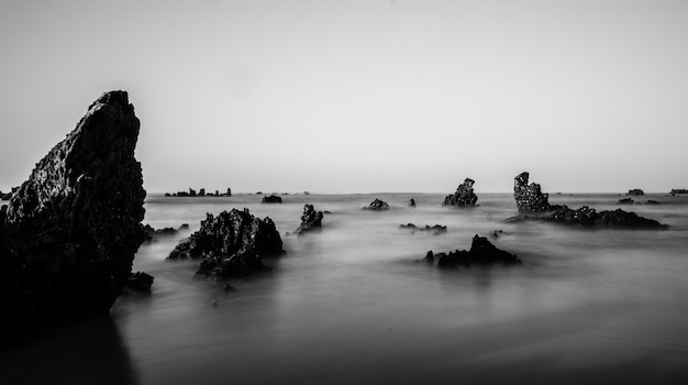 Tir en niveaux de gris de formations rocheuses dans la mer