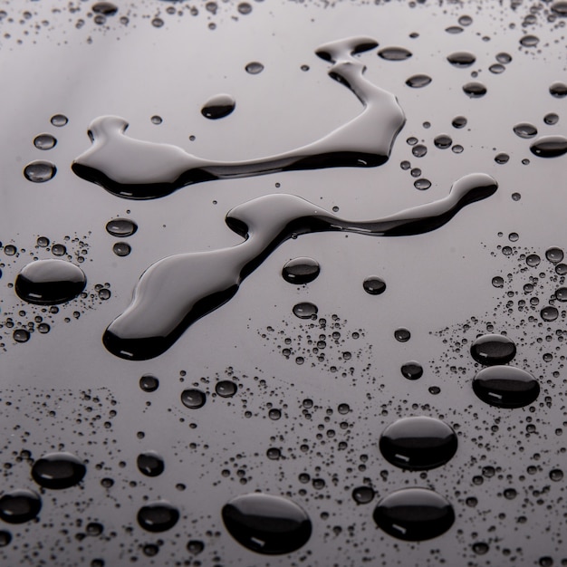 Photo gratuite tir en noir et blanc de gouttes de liquide sur une surface