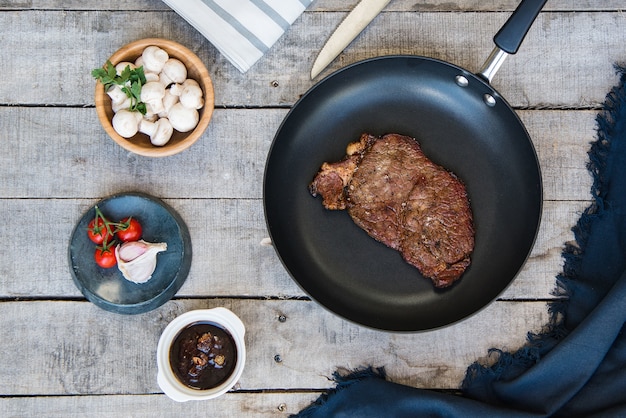 Tir d'un steak grillé dans le stylo et quelques champignons