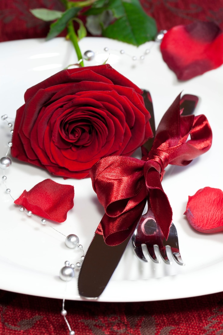 Photo gratuit tir vertical d'une assiette avec une rose rouge sur une table de fête