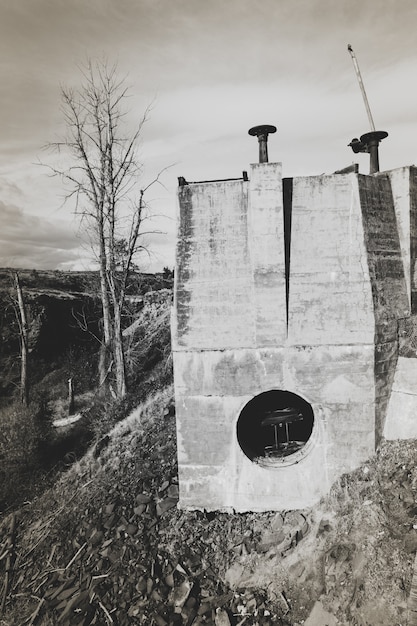 Photo gratuite tir vertical d'un bâtiments sur la colline avec un ciel nuageux en arrière-plan en noir et blanc