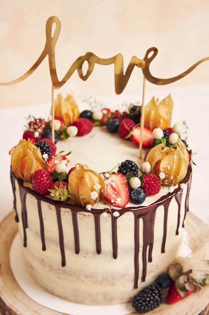 Tir vertical d'un beau gâteau de mariage avec goutte à goutte de chocolat aux fruits et avec topper Love