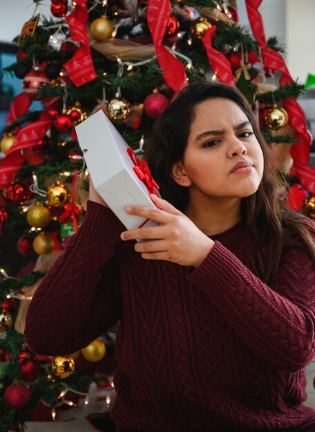 Tir vertical d'une belle jeune femme tenant un cadeau de Noël