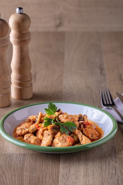 Tir vertical d'un bol de soupe au poulet et aux légumes et quelques épices sur une surface en bois