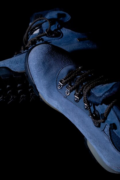 Tir vertical de bottes de randonnée d'hiver bleu sur fond noir