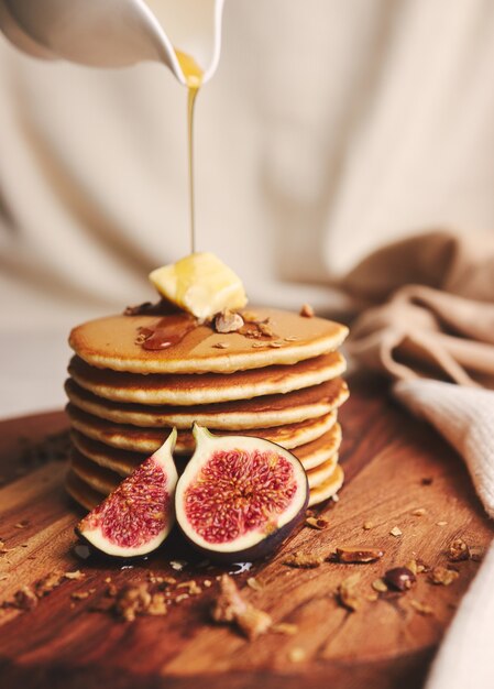 Tir vertical de crêpes au sirop, beurre et noix grillées sur une plaque en bois