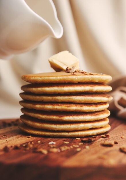 Tir vertical de délicieuses crêpes au beurre, figues et noix rôties sur une plaque en bois